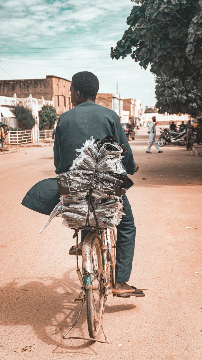 A man carries newspapers on a bicycle through the streets of Kano, Nigeria.