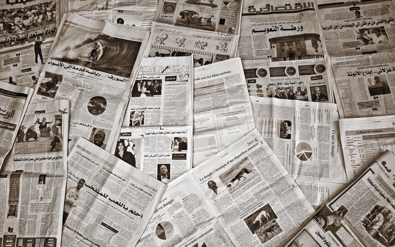 A variety of Arabic and French newspapers spread out, showcasing diverse articles and images.