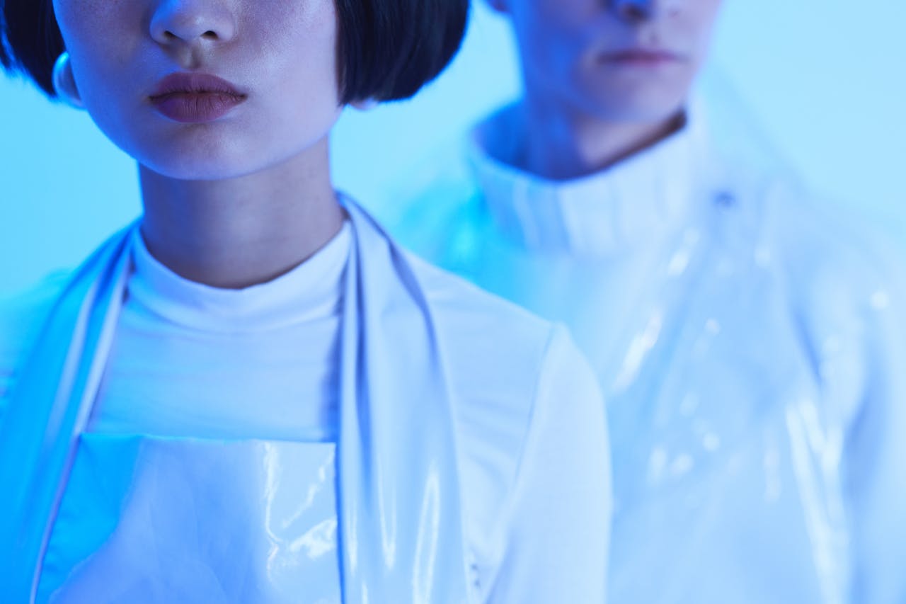 Stylish futuristic fashion photoshoot with models under blue lighting, showcasing modern aesthetics.