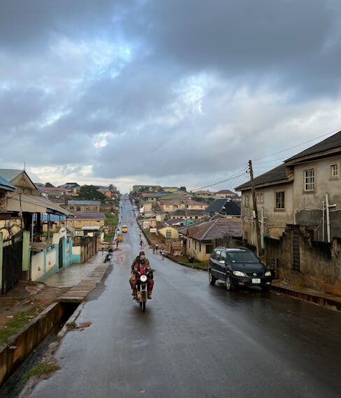 Street scene in urban neighborhood with motorbike and car during overcast weather.