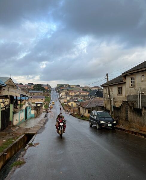 Street scene in urban neighborhood with motorbike and car during overcast weather.