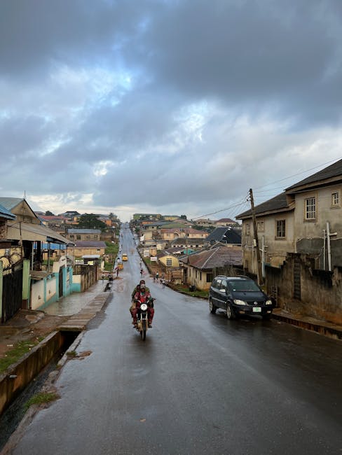 Street scene in urban neighborhood with motorbike and car during overcast weather.